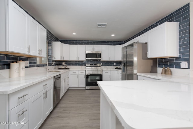 kitchen featuring stainless steel appliances, visible vents, decorative backsplash, and a sink