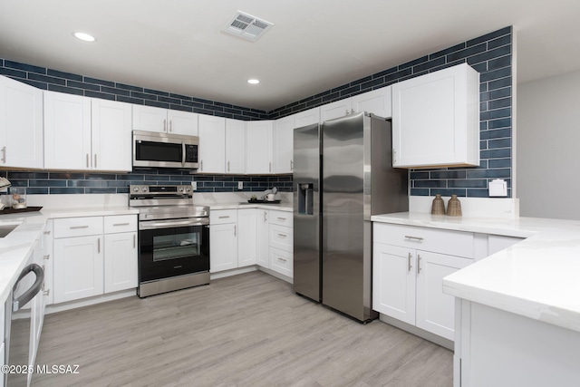 kitchen with visible vents, backsplash, white cabinets, and stainless steel appliances