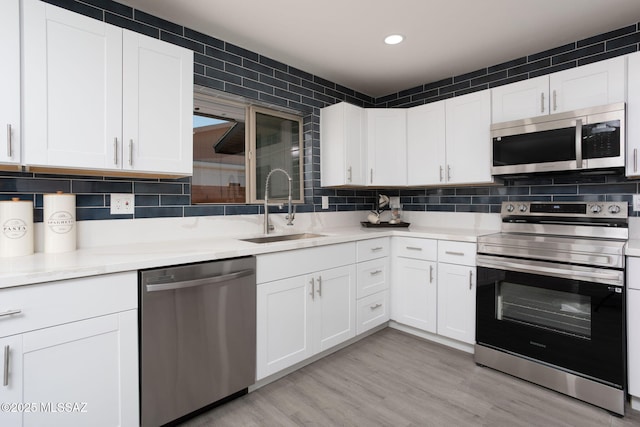 kitchen with a sink, white cabinetry, appliances with stainless steel finishes, and light countertops