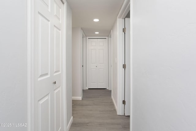 hallway featuring baseboards, recessed lighting, and light wood-type flooring