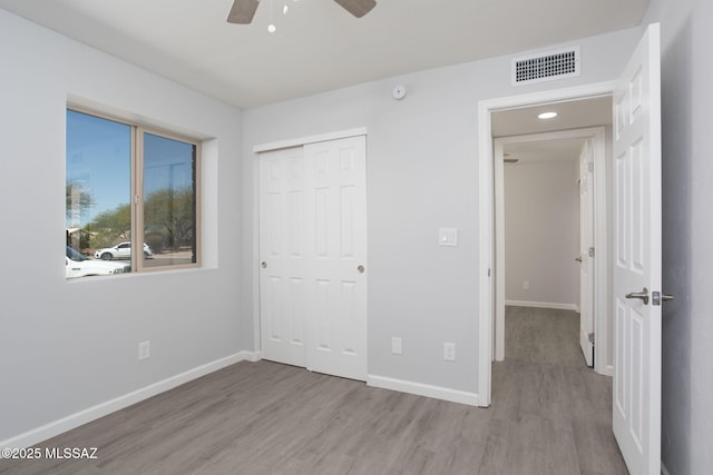 unfurnished bedroom featuring visible vents, baseboards, wood finished floors, and a closet