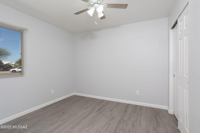 interior space with a ceiling fan, baseboards, and wood finished floors