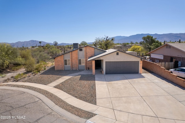 mid-century inspired home with a garage, a mountain view, driveway, and fence
