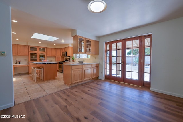 1402 N Camino Miraflores, Tucson, AZ 85745 - kitchen featuring stainless steel appliances, a skylight, light wood-style flooring, glass insert cabinets, and recessed lighting