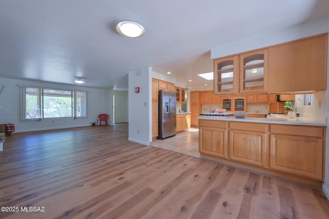 1402 N Camino Miraflores, Tucson, AZ 85745 - kitchen featuring stainless steel fridge with ice dispenser, open floor plan, glass insert cabinets, light wood finished floors, and a peninsula