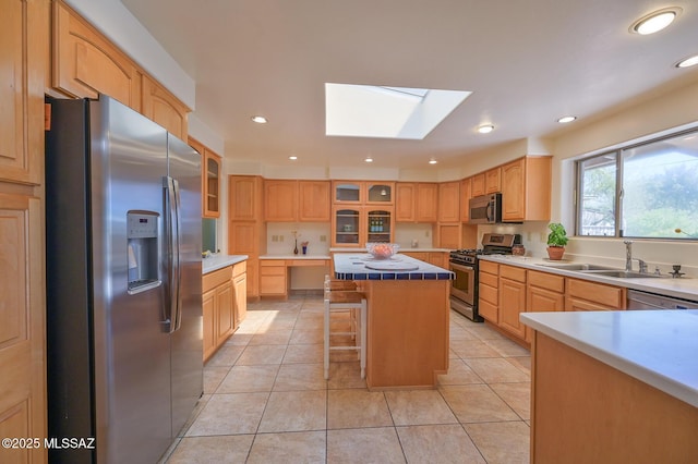 1402 N Camino Miraflores, Tucson, AZ 85745 - kitchen featuring appliances with stainless steel finishes, a sink, a skylight, a center island, and glass insert cabinets