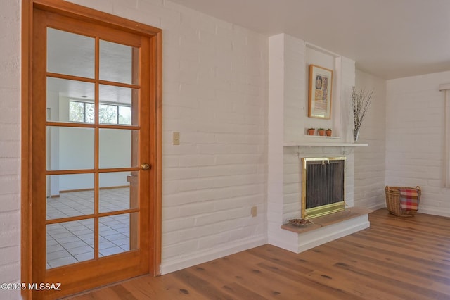 1402 N Camino Miraflores, Tucson, AZ 85745 - unfurnished living room with wood finished floors, a fireplace, baseboards, and brick wall