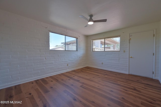 1402 N Camino Miraflores, Tucson, AZ 85745 - unfurnished room featuring brick wall, wood finished floors, and a ceiling fan