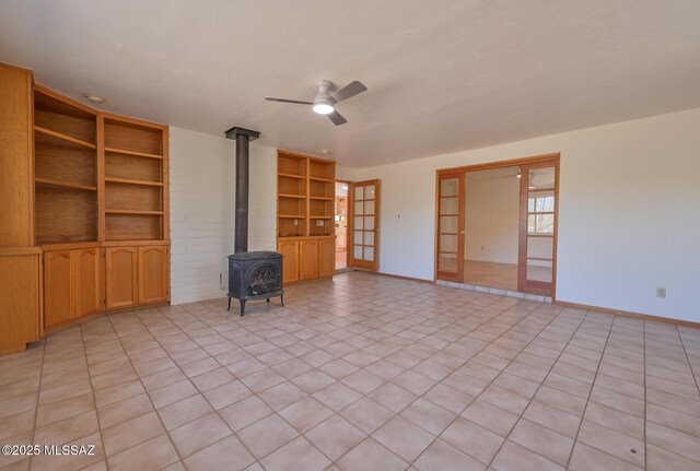 1402 N Camino Miraflores, Tucson, AZ 85745 - unfurnished living room with a wood stove, ceiling fan, built in shelves, and baseboards