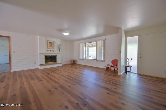 1402 N Camino Miraflores, Tucson, AZ 85745 - unfurnished living room featuring wood finished floors, a glass covered fireplace, brick wall, and baseboards