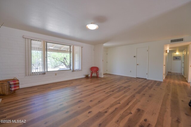 1402 N Camino Miraflores, Tucson, AZ 85745 - empty room with wood finished floors, brick wall, and baseboards