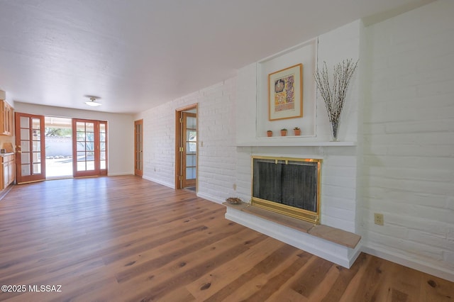 1402 N Camino Miraflores, Tucson, AZ 85745 - unfurnished living room with a glass covered fireplace, wood finished floors, baseboards, and brick wall