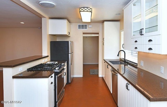 kitchen featuring dark countertops, a sink, stainless steel appliances, baseboards, and visible vents