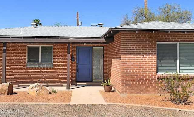 view of front of home featuring brick siding and a shingled roof