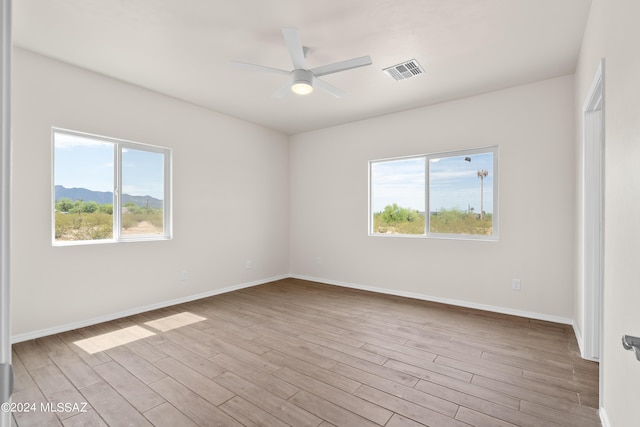 unfurnished room with plenty of natural light, ceiling fan, and wood finished floors