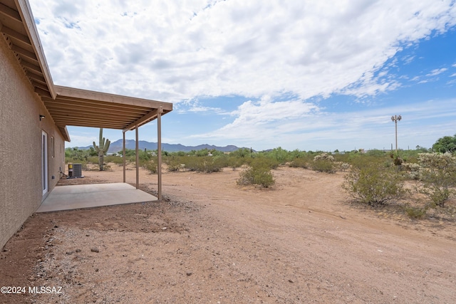 view of yard with central AC unit, a mountain view, and a patio