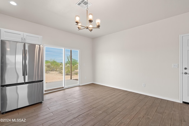 spare room featuring visible vents, recessed lighting, wood finished floors, baseboards, and a notable chandelier