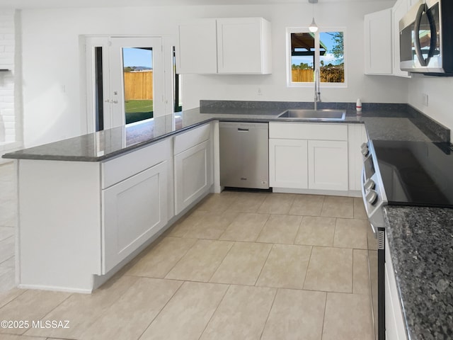 kitchen with a sink, white cabinets, a peninsula, and stainless steel appliances