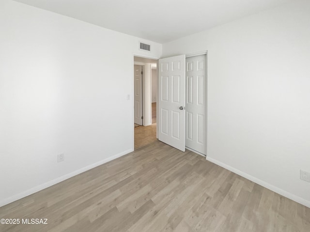 unfurnished bedroom featuring a closet, visible vents, light wood-type flooring, and baseboards