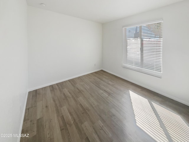 unfurnished room with baseboards and wood finished floors