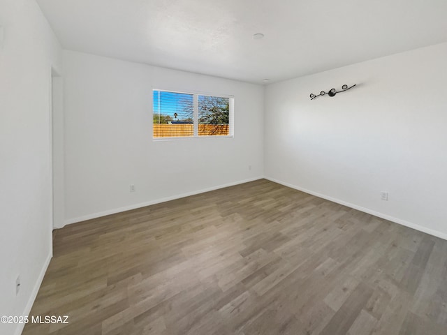 unfurnished room with baseboards and wood finished floors