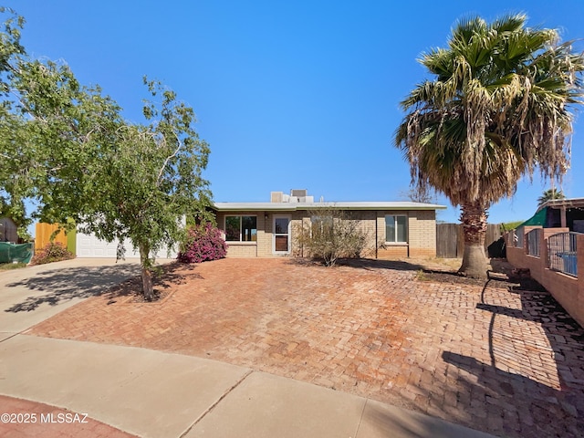 single story home with driveway, fence, and brick siding