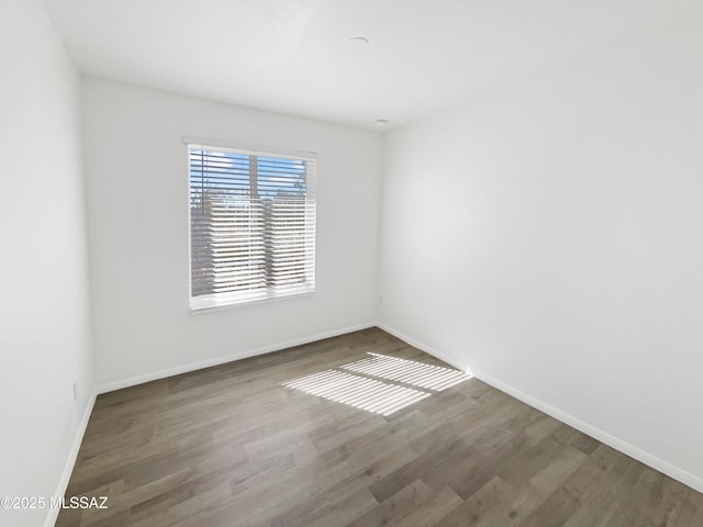 empty room featuring wood finished floors and baseboards