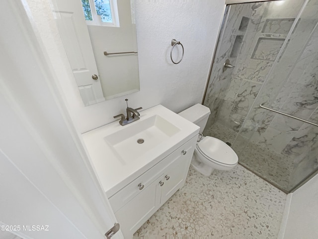 bathroom with toilet, vanity, and a marble finish shower