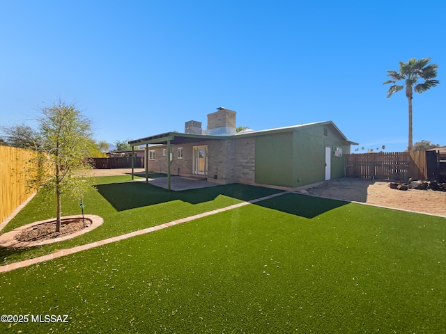 back of property featuring a patio area, a fenced backyard, a chimney, and a lawn