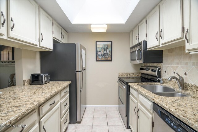kitchen featuring stainless steel dishwasher, a sink, baseboards, backsplash, and light tile patterned floors