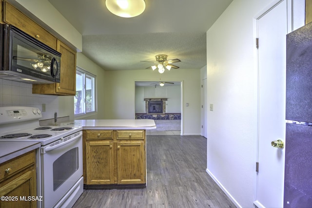 3061 W Avenida Cresta, Tucson, AZ 85745 - kitchen with white electric range oven, a peninsula, black microwave, ceiling fan, and brown cabinetry