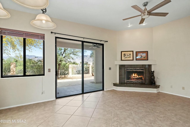 11460 N Palmetto Dunes Ave, Tucson, AZ 85737 - unfurnished living room with ceiling fan, a warm lit fireplace, tile patterned flooring, and baseboards