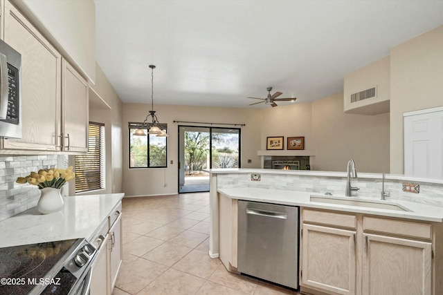11460 N Palmetto Dunes Ave, Tucson, AZ 85737 - kitchen featuring a sink, tasteful backsplash, a ceiling fan, appliances with stainless steel finishes, and a lit fireplace