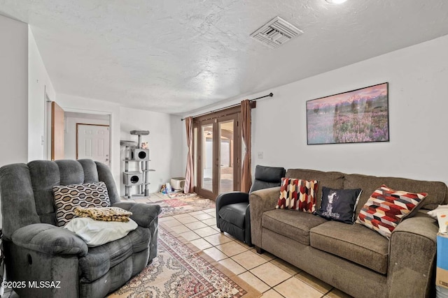 living area with visible vents, light tile patterned flooring, and a textured ceiling