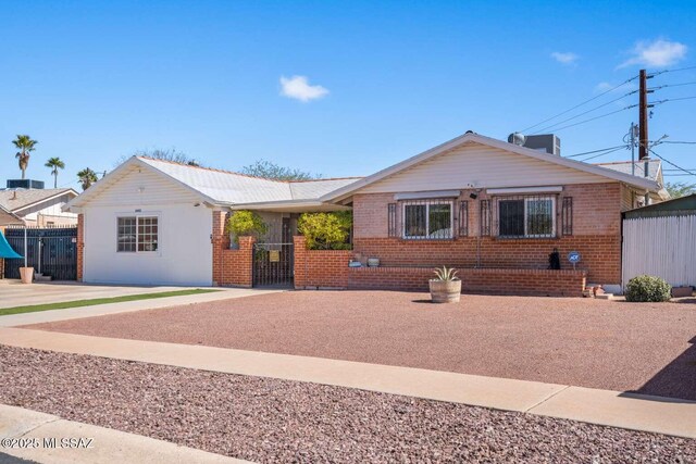 ranch-style house featuring brick siding, central air condition unit, and fence