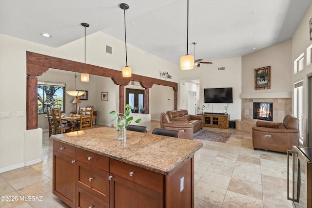 kitchen with visible vents, a ceiling fan, brown cabinetry, pendant lighting, and a kitchen island