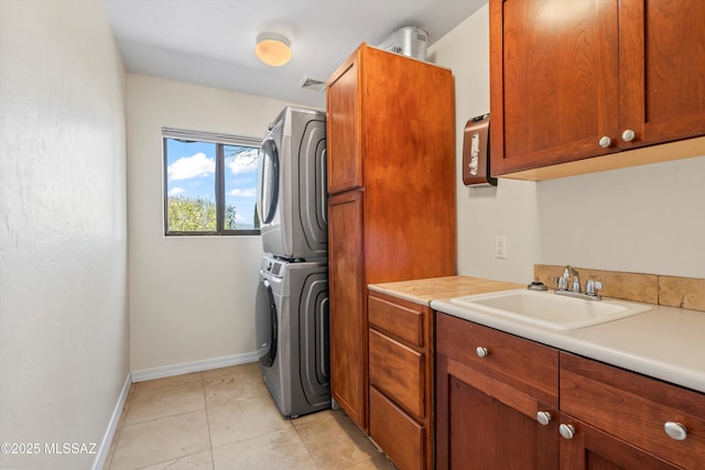 clothes washing area featuring baseboards, visible vents, stacked washer / drying machine, cabinet space, and a sink