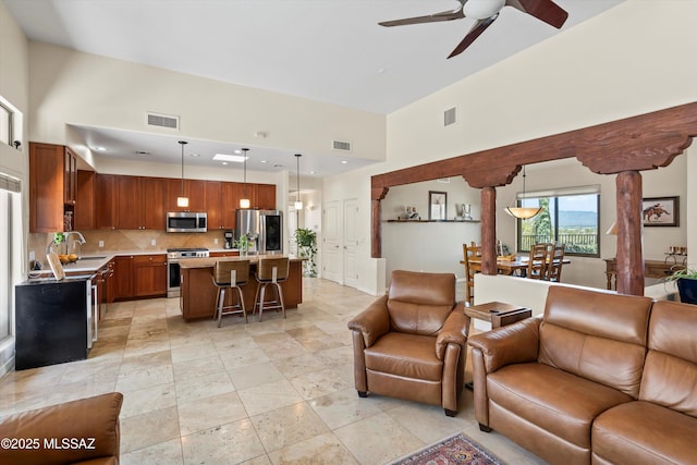 living room featuring visible vents, a high ceiling, and a ceiling fan