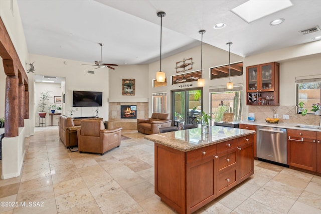 kitchen with visible vents, glass insert cabinets, dishwasher, a tiled fireplace, and a sink