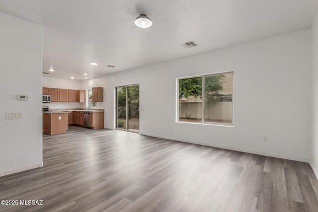 20950 E Frontier Rd, Red Rock, AZ 85145 - unfurnished living room with wood finished floors, baseboards, recessed lighting, and a sink