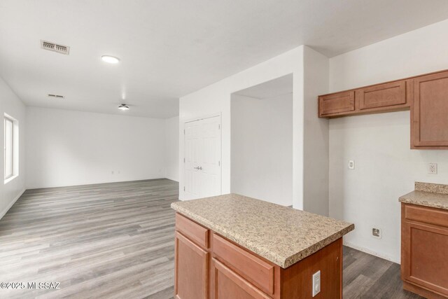 20950 E Frontier Rd, Red Rock, AZ 85145 - kitchen featuring wood finished floors, light countertops, a center island, and brown cabinetry