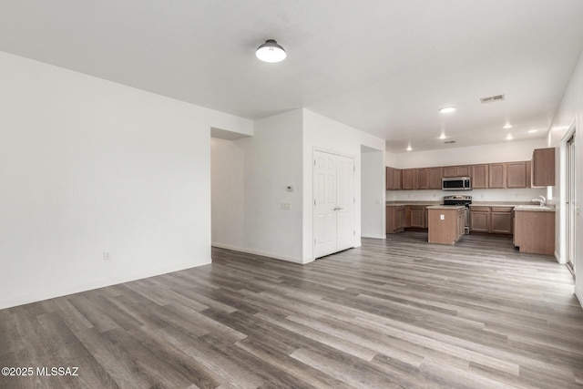 20950 E Frontier Rd, Red Rock, AZ 85145 - unfurnished living room featuring wood finished floors, a sink, baseboards, and recessed lighting