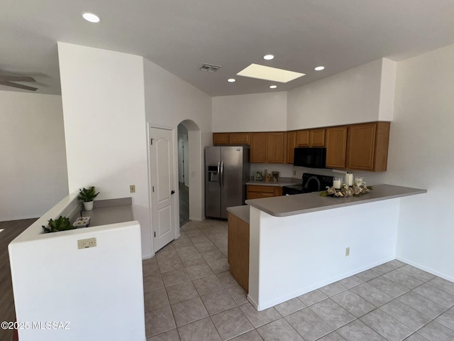 7456 E Placita Del Espiritu, Tucson, AZ 85715 - kitchen featuring stainless steel fridge with ice dispenser, black microwave, stove, brown cabinets, and a peninsula
