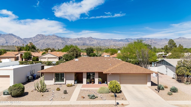 single story home with stucco siding, fence, an attached garage, a mountain view, and driveway
