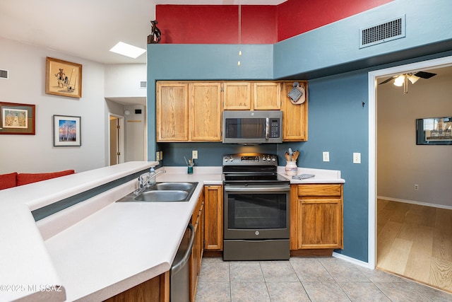 kitchen featuring visible vents, appliances with stainless steel finishes, light countertops, a sink, and baseboards