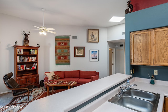 kitchen featuring visible vents, a sink, light countertops, a ceiling fan, and a skylight