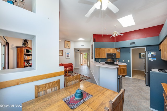 dining space with visible vents, ceiling fan, light tile patterned floors, and a skylight