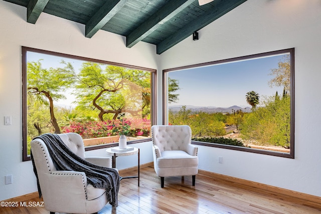 living area with a mountain view, wood ceiling, vaulted ceiling with beams, and wood finished floors