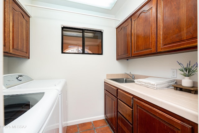 clothes washing area featuring independent washer and dryer, dark tile patterned flooring, a sink, baseboards, and cabinet space