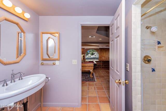 bathroom featuring baseboards, tile patterned flooring, visible vents, a tile shower, and a sink